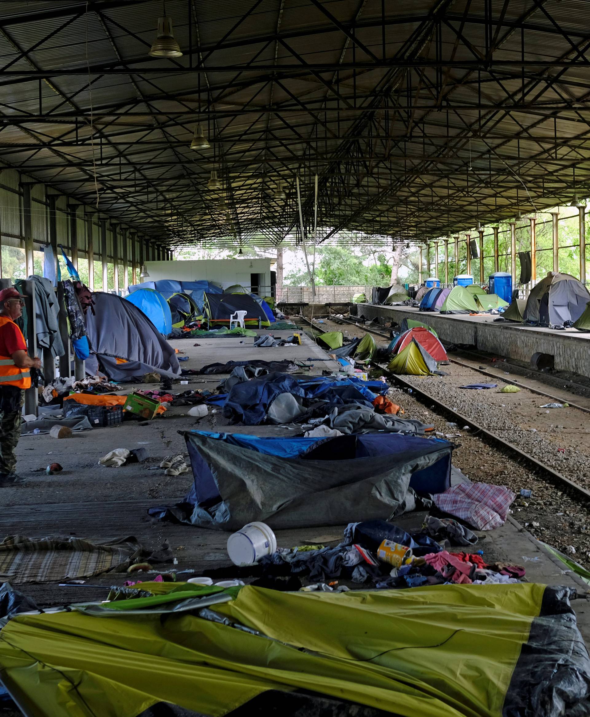 A worker stands next to empty tents during a police operation to evacuate a migrants' makeshift camp at the Greek-Macedonian border near the village of Idomeni