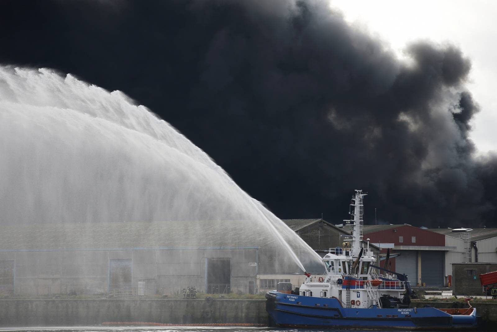 Firefighting vessel sprays water after a large fire broke out at the factory of Lubrizol in Rouen