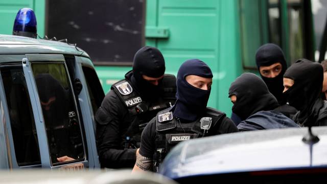 Police officers gather outside during a raid in an apartment building at Kreuzberg district in Berlin