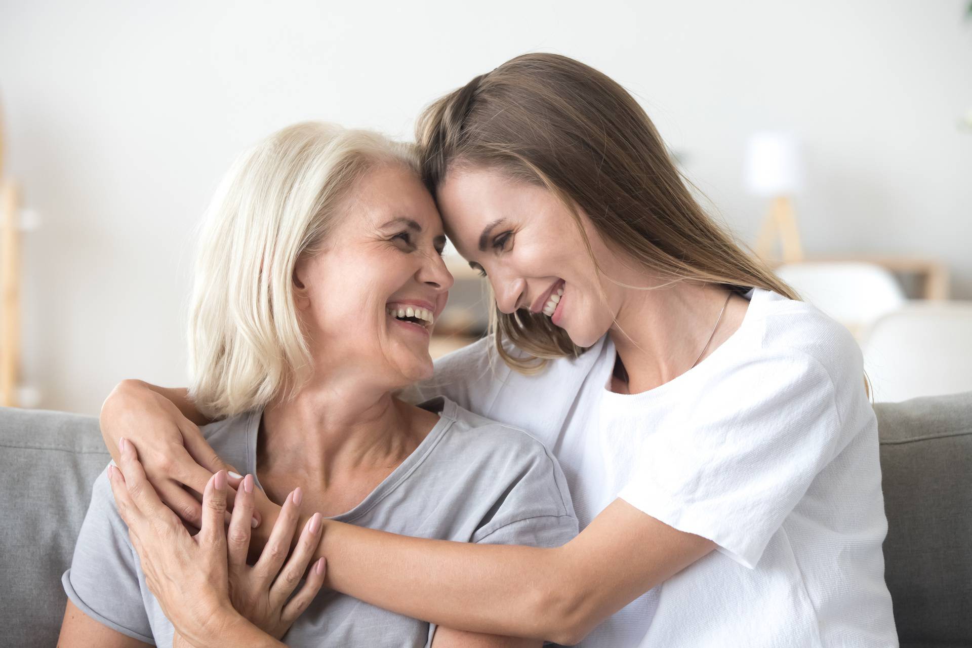 Happy loving older mother and grown millennial daughter laughing embracing