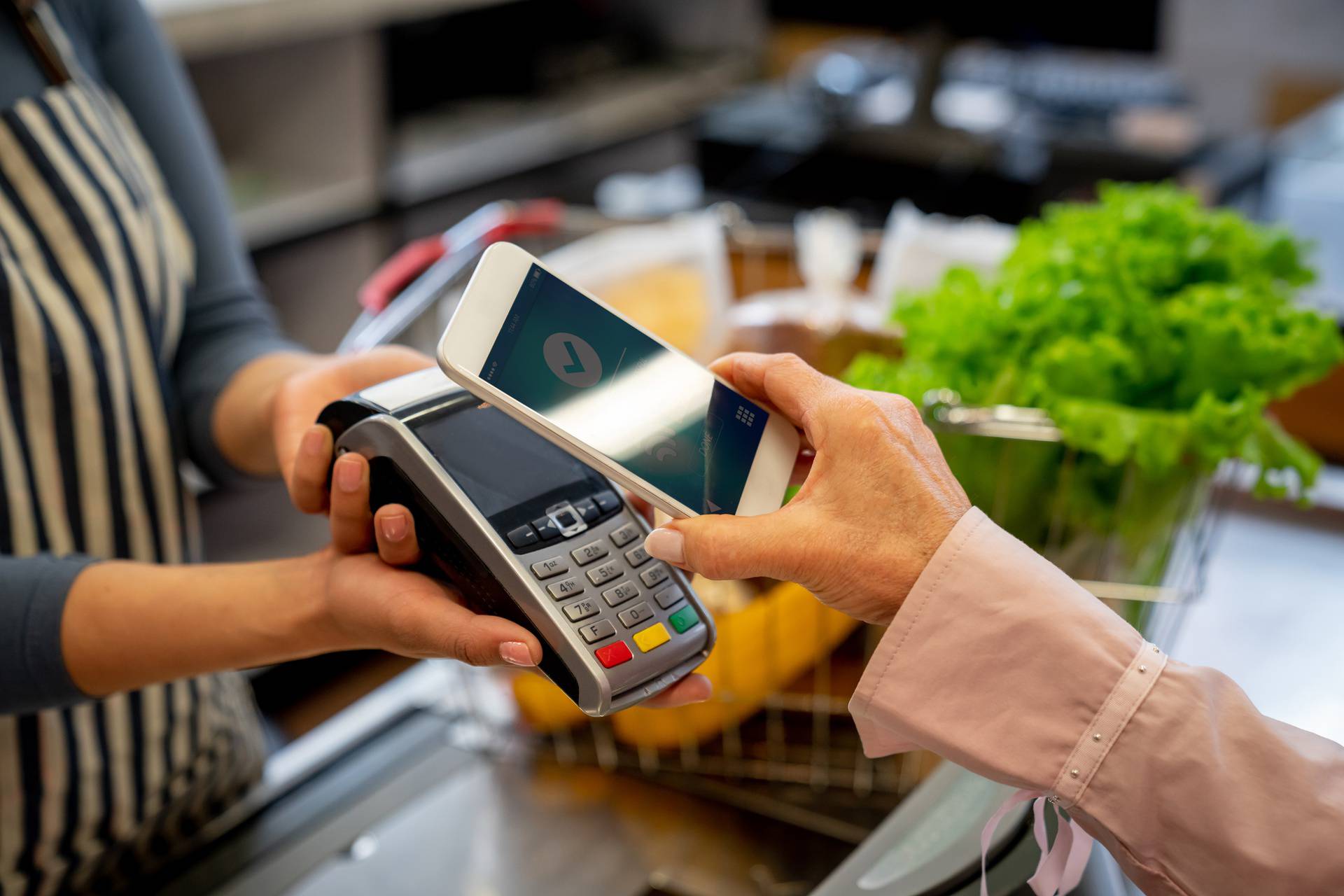 Unrecognizable female customer paying for groceries with smartphone