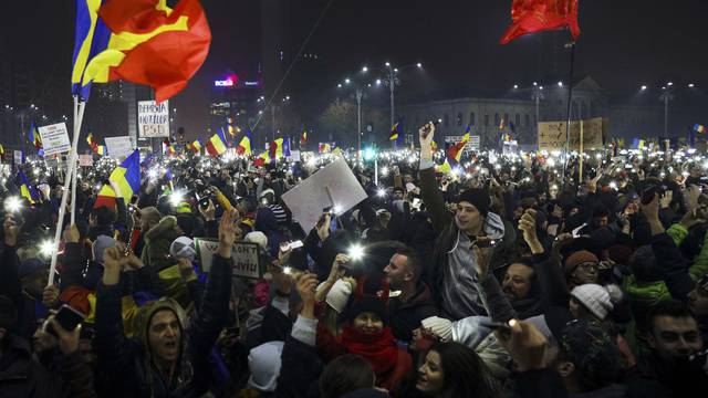 Protesters light their mobiles as they take part in a demonstration in Bucharest