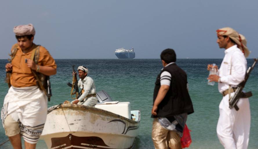 FILE PHOTO: Armed men stand on the beach as the Galaxy Leader commercial ship, seized by Yemen's Houthis last month, is anchored off the coast of al-Salif