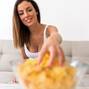 A young beautiful Woman relaxing on a sofa having potato Chips  