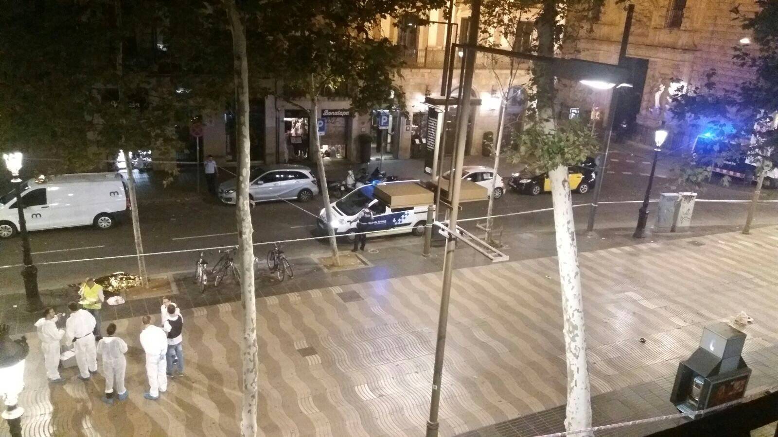 Forensic workers stand near a dead person at the scene after a van crashed into pedestrians near the Las Ramblas avenue in central Barcelona