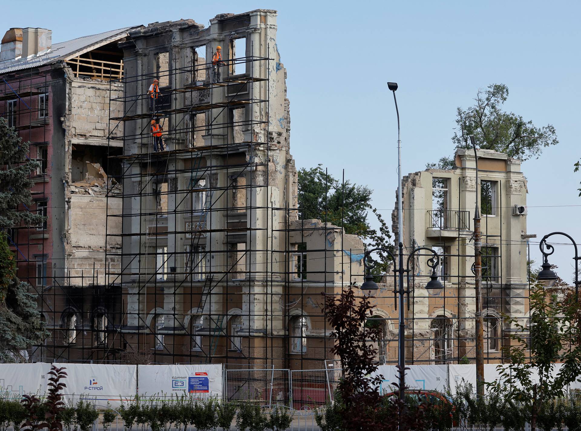 A construction crew works on a destroyed building in Mariupol