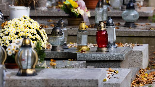 Candles and flowers on graves in the cemetery during the All Saint's Day. Taken during the day, natual light.