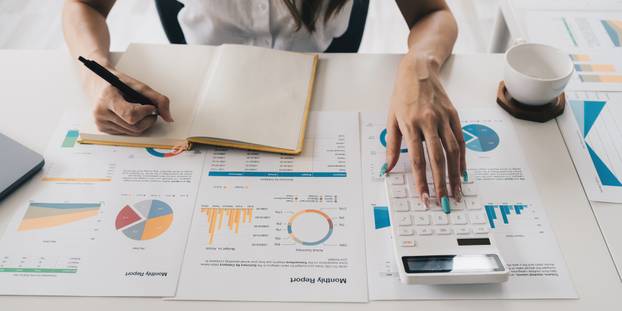 Businesswoman analyzes company's financial system and using calculator.