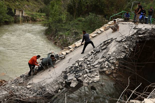 People cross a damaged bridge in Zrarieh