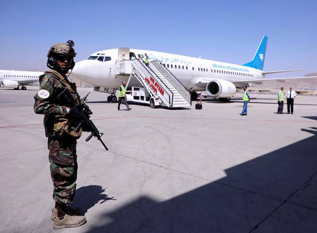 A member of Taliban forces stands guard next to a plane at Hamid Karzai International Airport in Kabul