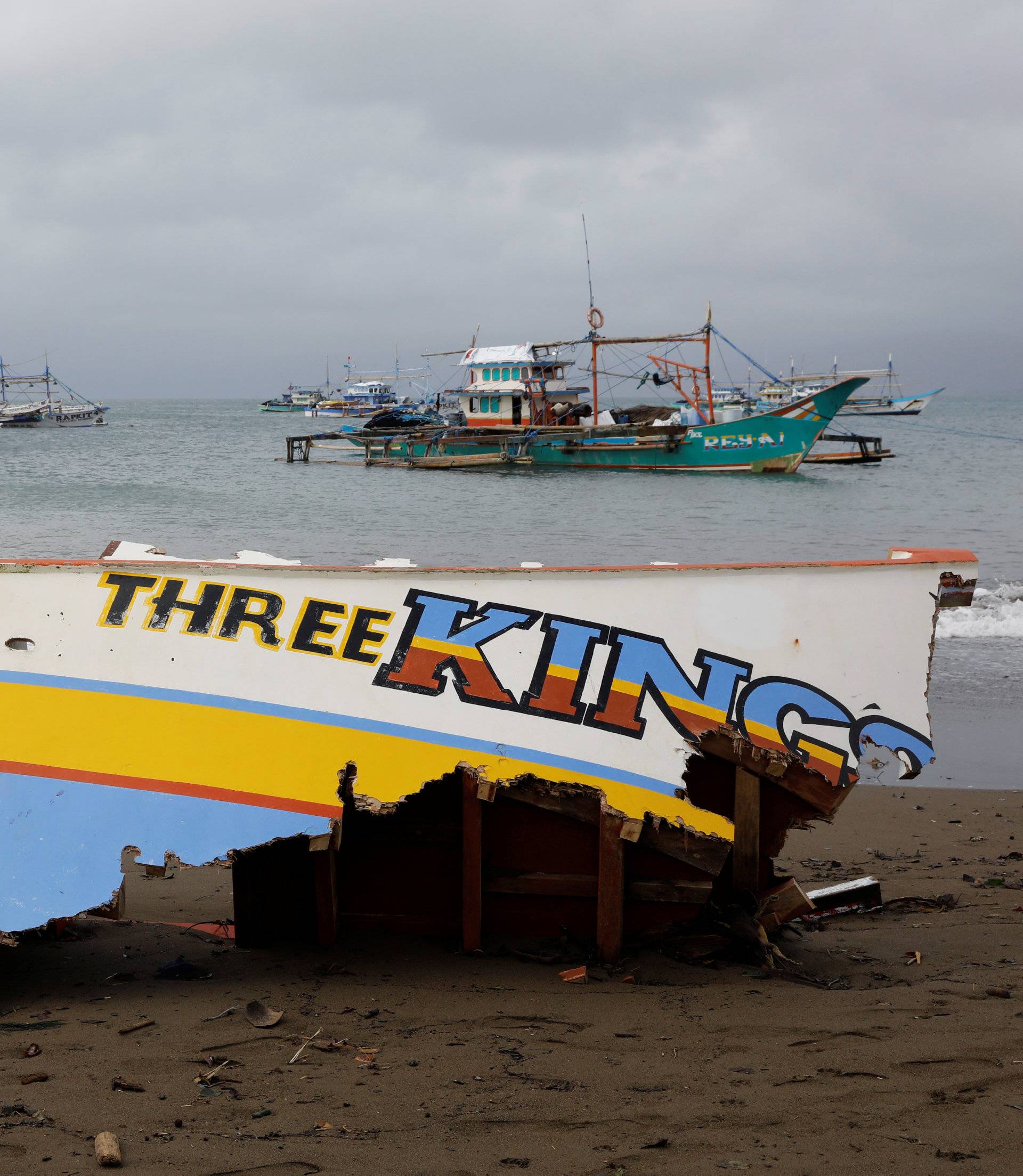 The remains of a passenger boat capsized during a typhoon last month is pictured overlooking passenger boats near the shore after all ferry service were cancelled, a day after a Philippine vessel was capsized because of bad weather in Infanta, Quezon