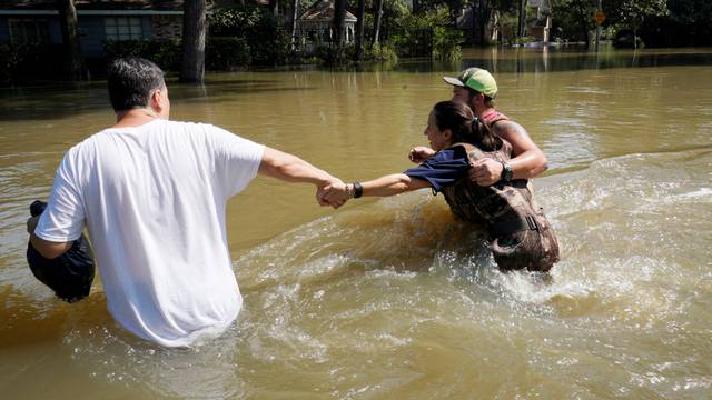 Melissa Ramirez struggles against the current flowing down a flooded street helped by Edward Ramirez and Cody Collinsworth as she tried to return to her home for the first time since Harvey floodwaters arrived in Houston