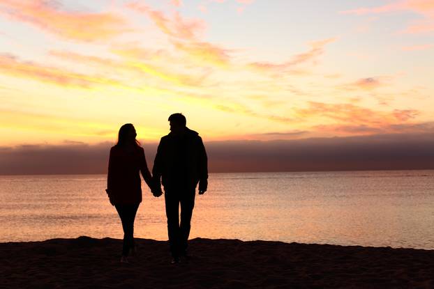 Couple silhouettes walking together at sunset