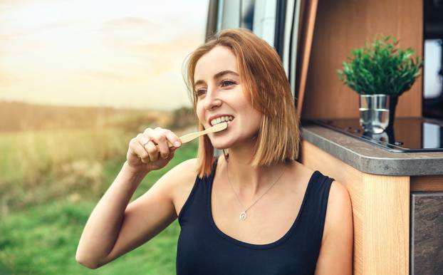 Young,Woman,Brushing,Her,Teeth,With,A,Bamboo,Toothbrush,Outdoors
