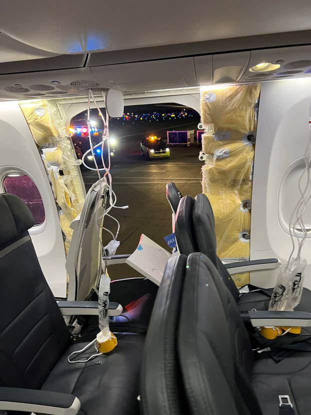 Passenger oxygen masks hang from the roof next to a missing window and a portion of a side wall of an Alaska Airlines Flight 1282, in Portland, Oregon