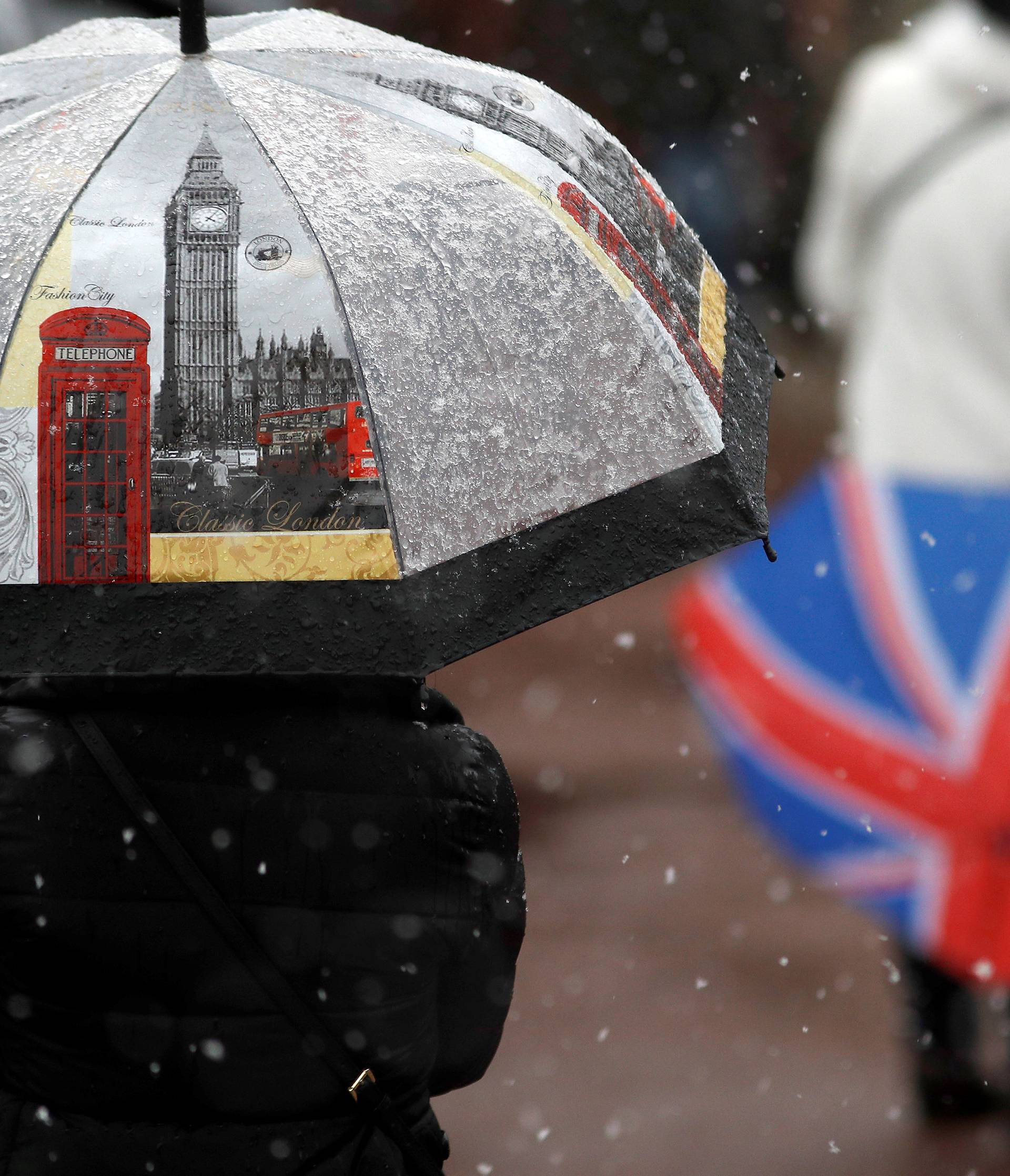 Tourists stand in the snow outside Buckingham Palace, London