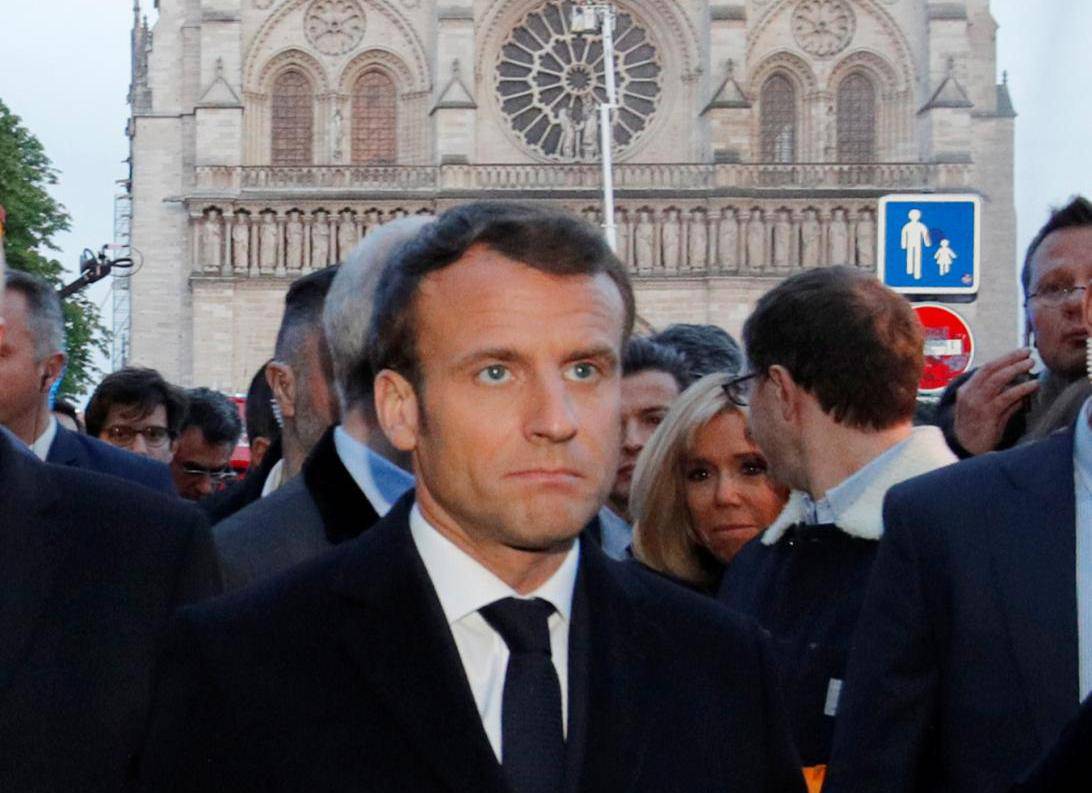 French President Emmanuel Macron walks near the Notre Dame Cathedral as its burns in Paris