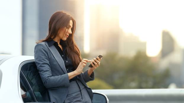 Business,Woman,Uses,Smartphone,While,Leaning,On,Her,Premium,Class