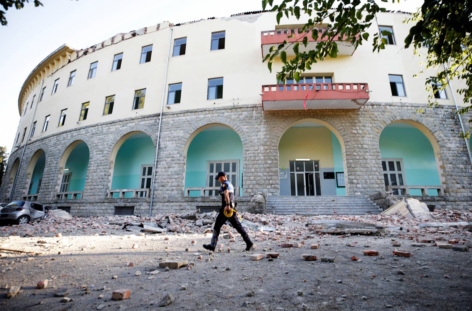 A police officer walks past a damaged building after an earthquake in Tirana