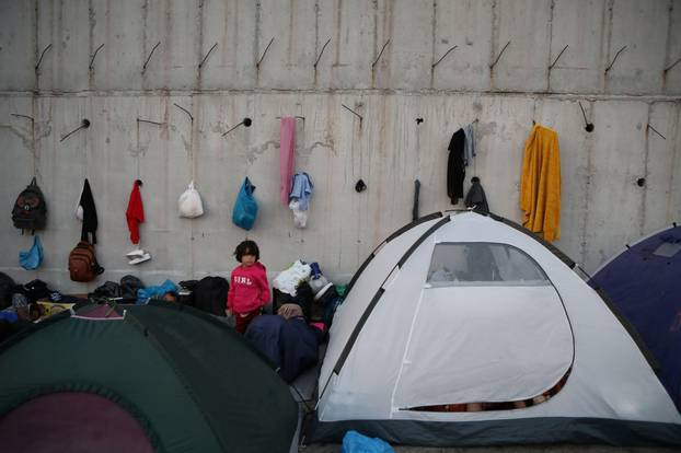 A girl stands next to tents as refugees and migrants from the destroyed Moria camp find shelter in an area near a new temporary camp on the island of Lesbos