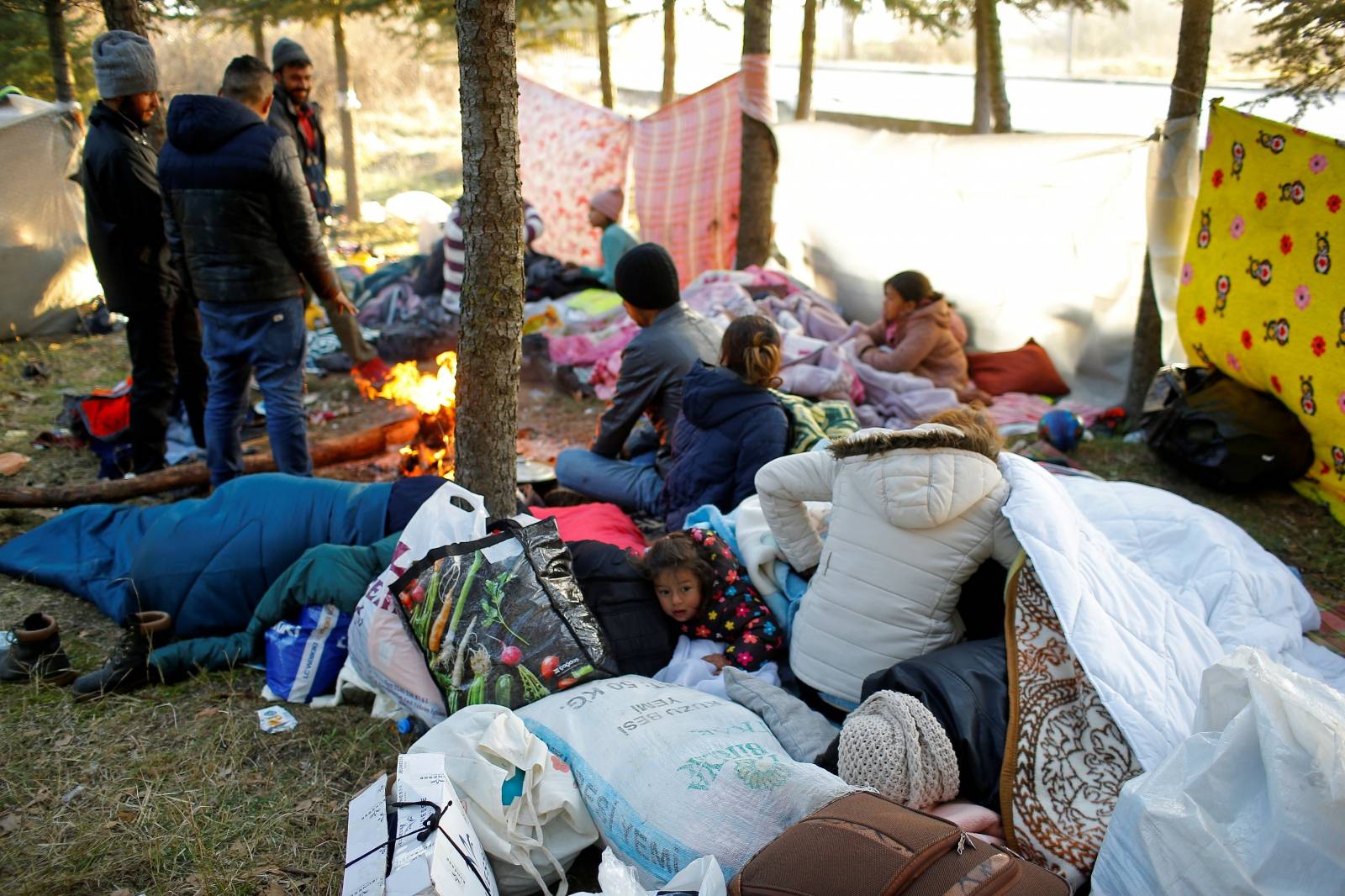 Migrants stand by a fire near Turkey's Pazarkule border crossing with Greece's Kastanies, near Edirne