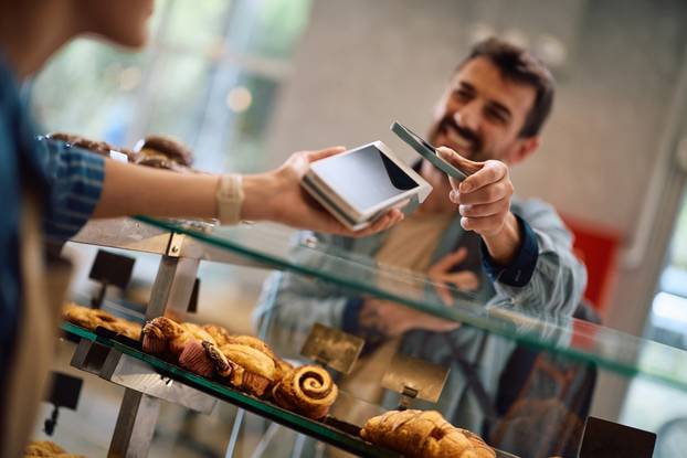 Close,Up,Of,Man,Using,Cell,Phone,While,Paying,In