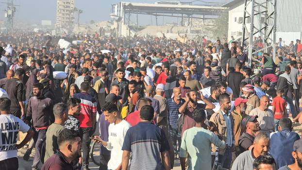 Palestinians gather at an aid distribution center in Deir Al-Balah, in the Gaza Strip