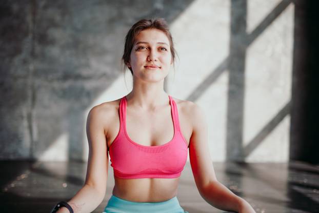 Woman practicing yoga in lotus pose indoor. Fit girl in sportswear sitting in Padmasana