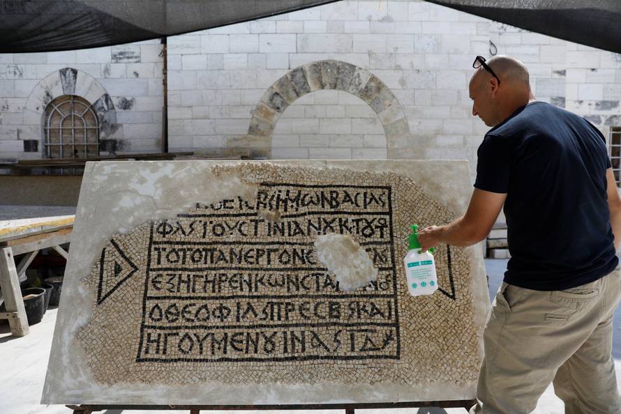 A conservationist works on a 1500-year-old mosaic floor bearing a Greek writing, discovered near Damascus Gate in Jerusalem's Old City, as it is displayed at the Rockefeller Museum in Jerusalem