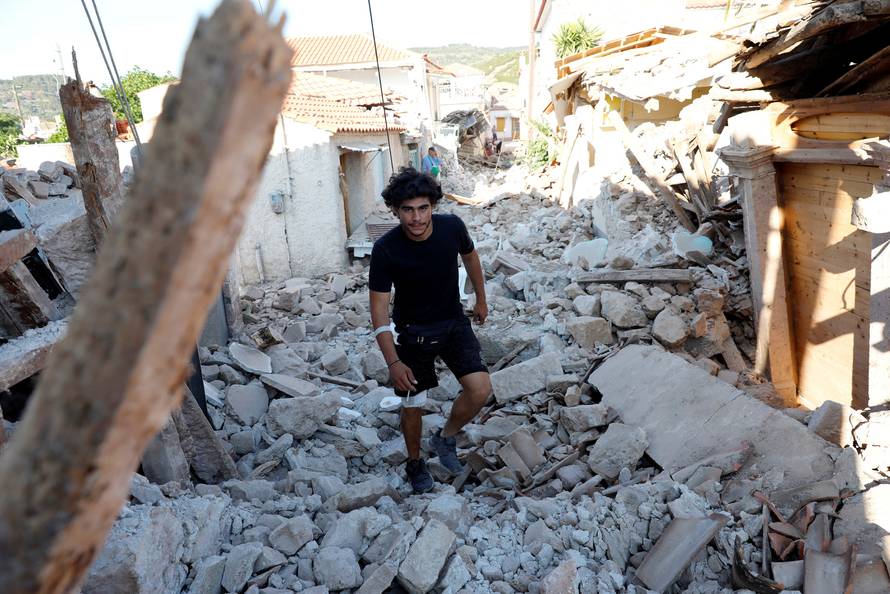 A man walks among collapsed buildings at the village of Vrissa on the Greek island of Lesbos, Greece, after a strong earthquake shook the eastern Aegean