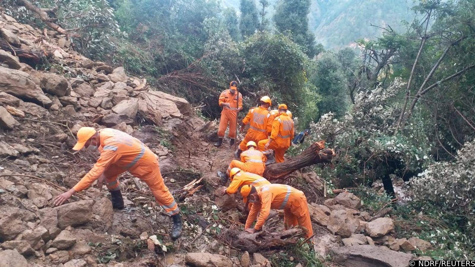 Members of National Disaster Response Force search the debris after a landslide caused by heavy rains at Dungri village