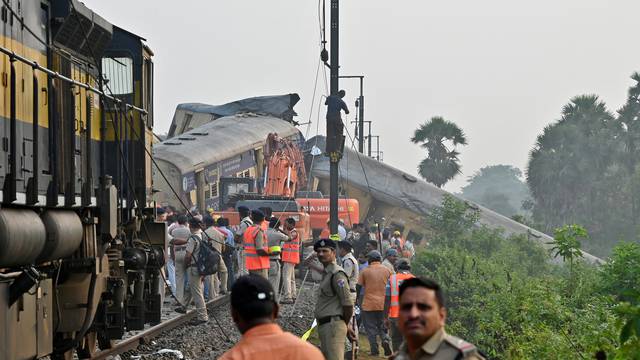 Rescue workers and police officials stand next to damaged coaches following a collision between two passenger trains in Vizianagaram
