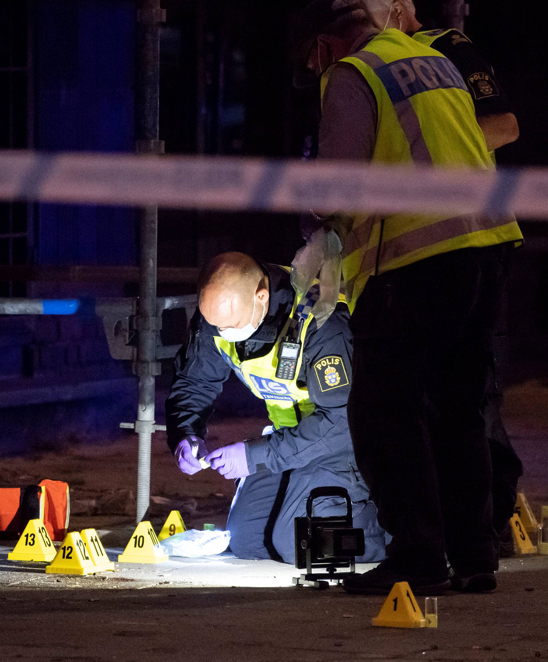 Police forensics investigate the scene after people were shot and injured outside an Internet cafe in central Malmo