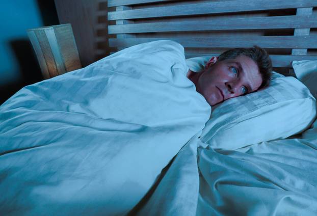 young sad and desperate man lying on bed crying depressed looking away thoughtful and pensive suffering depression problem and stress