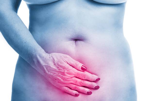 Senior woman touching abdomen over white background