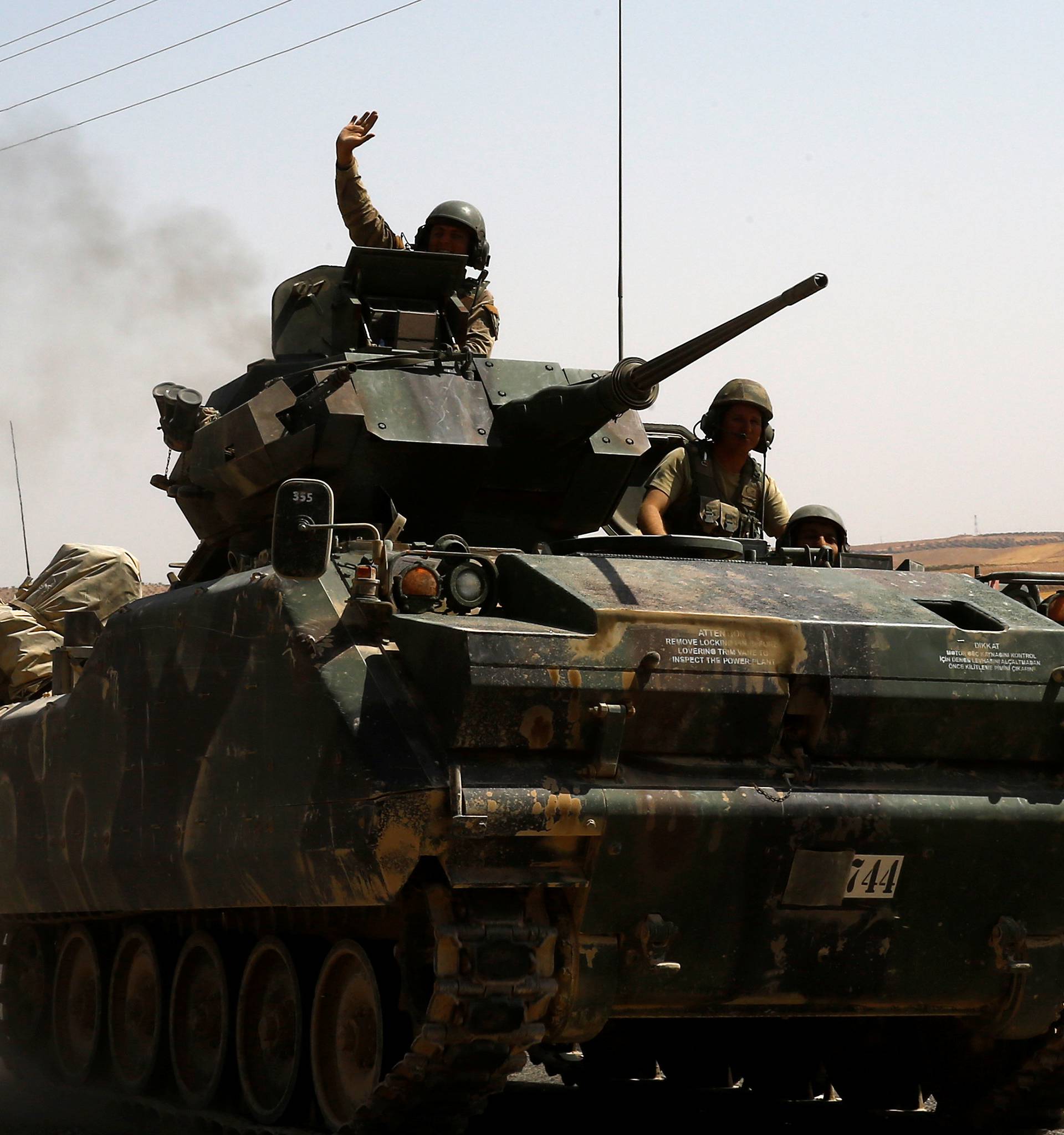 A Turkish soldier on an armoured personnel carrier waves as they drive from the border back to their base in Karkamis on the Turkish-Syrian border 