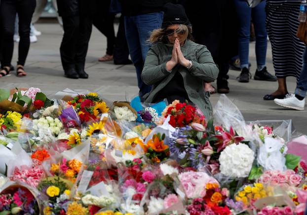 A woman sits in front of floral tributes on the south side of London Bridge near Borough Market after an attack left 7 people dead and dozens of injured in London