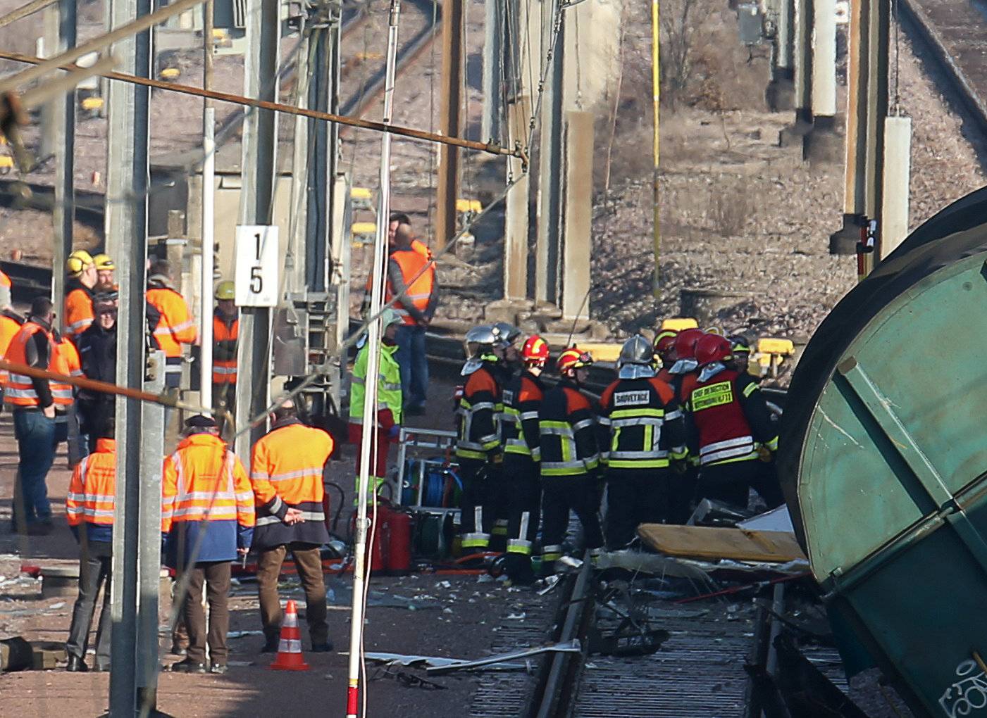 Rescuers stand next the wreckage of a passenger and freight train after a crash near Bettembourg