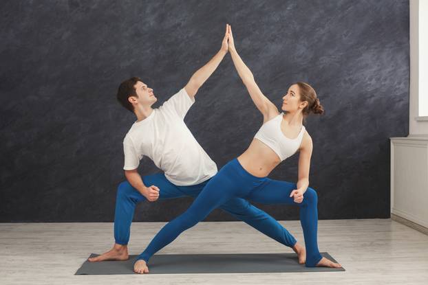 Young couple practicing yoga together in gym