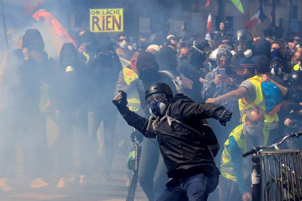 Tear gas floats around masked protesters during clashes before the start of the traditional May Day labour union march in Paris