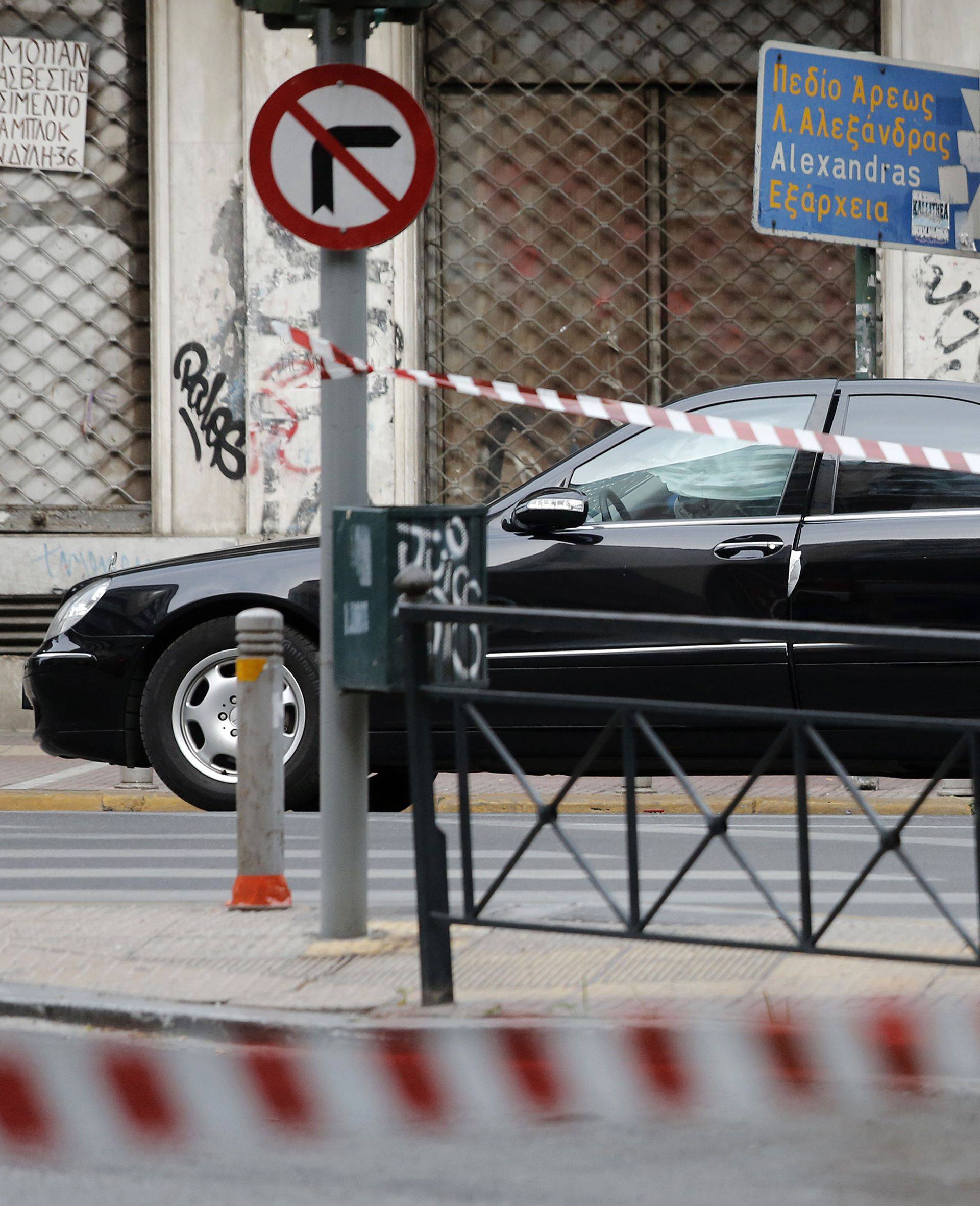 A police officer secures the area around the car of former Greek prime minister and former central bank chief Lucas Papademos following the detonation of an envelope injuring him and his driver, in Athens