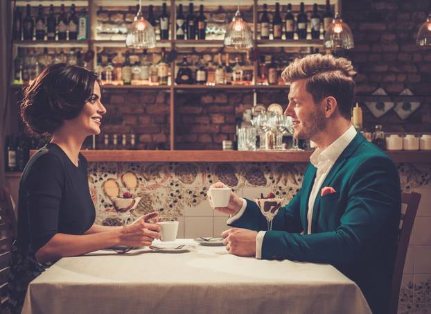Stylish wealthy couple having desert and coffee together in a restaurant.