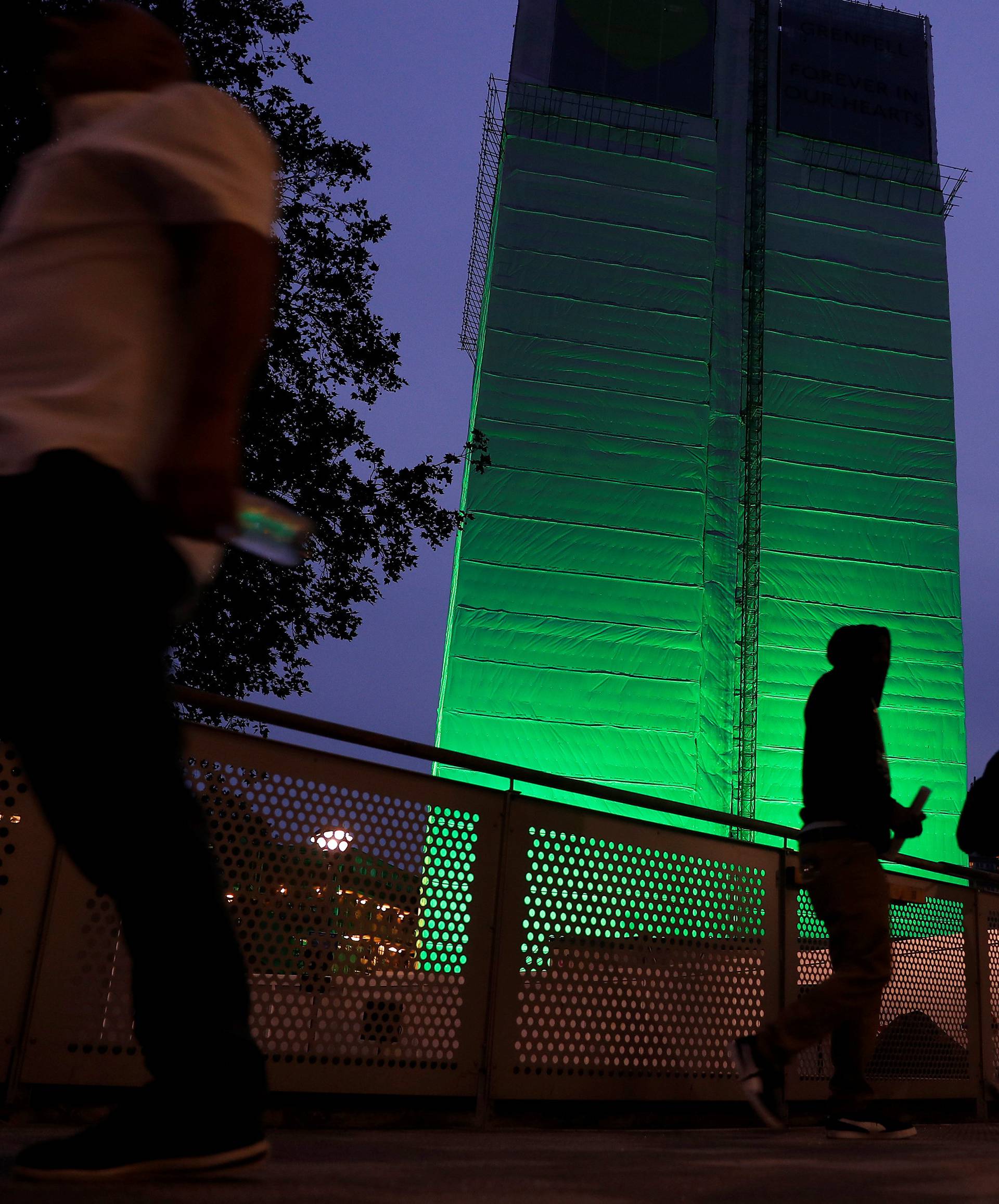 Grenfell Tower is seen covered and illuminated with green light one year after the tower fire in London