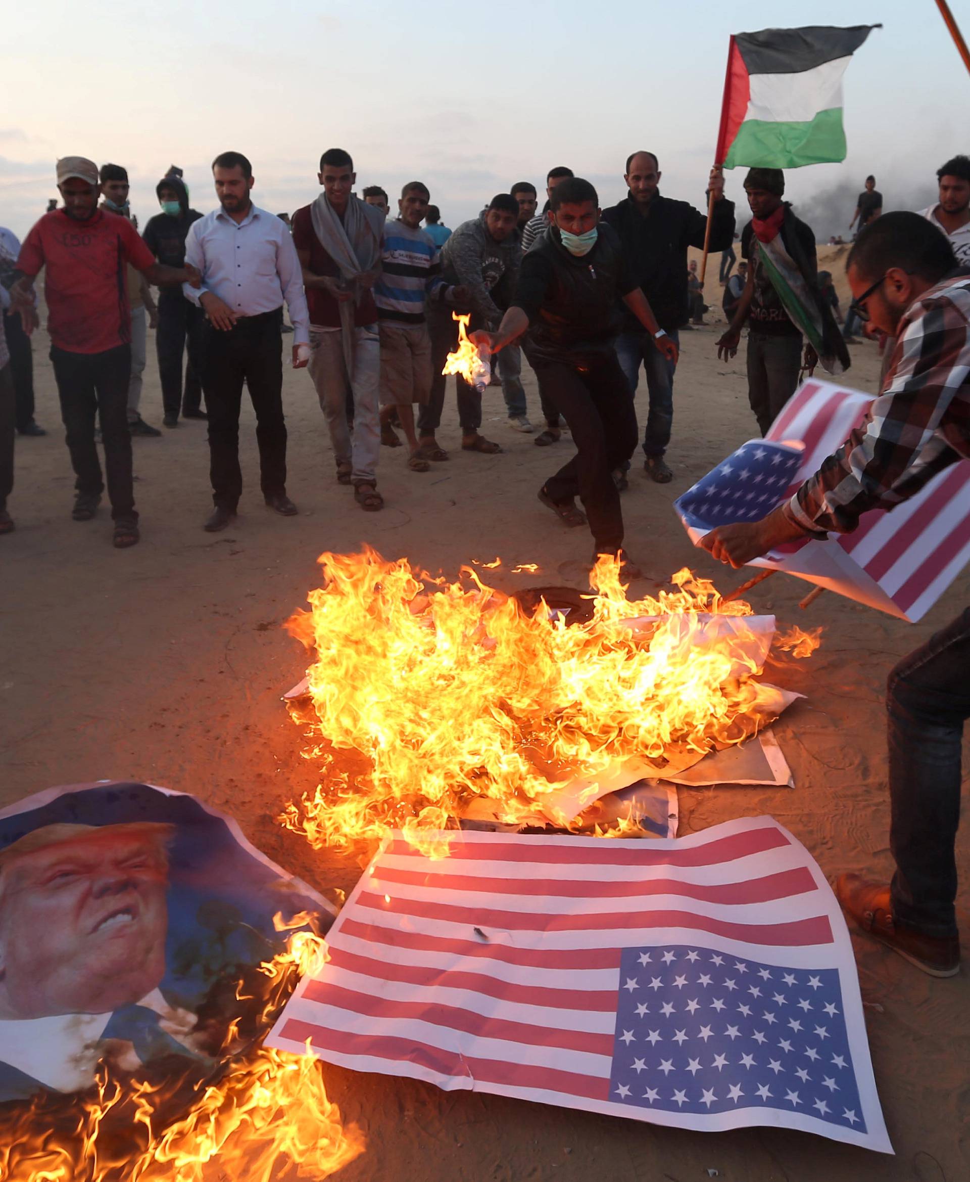 Palestinian demonstrators burn representations of U.S. flags and a poster of U.S. President Trump during a protest, at the Israel-Gaza border in the southern Gaza Strip