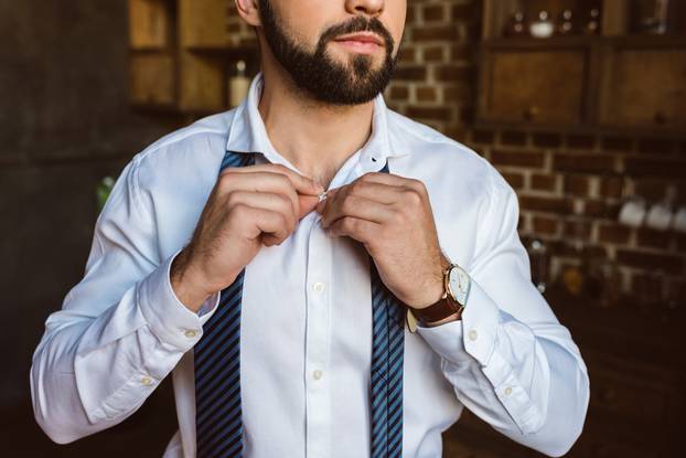 businessman fastening buttons on shirt