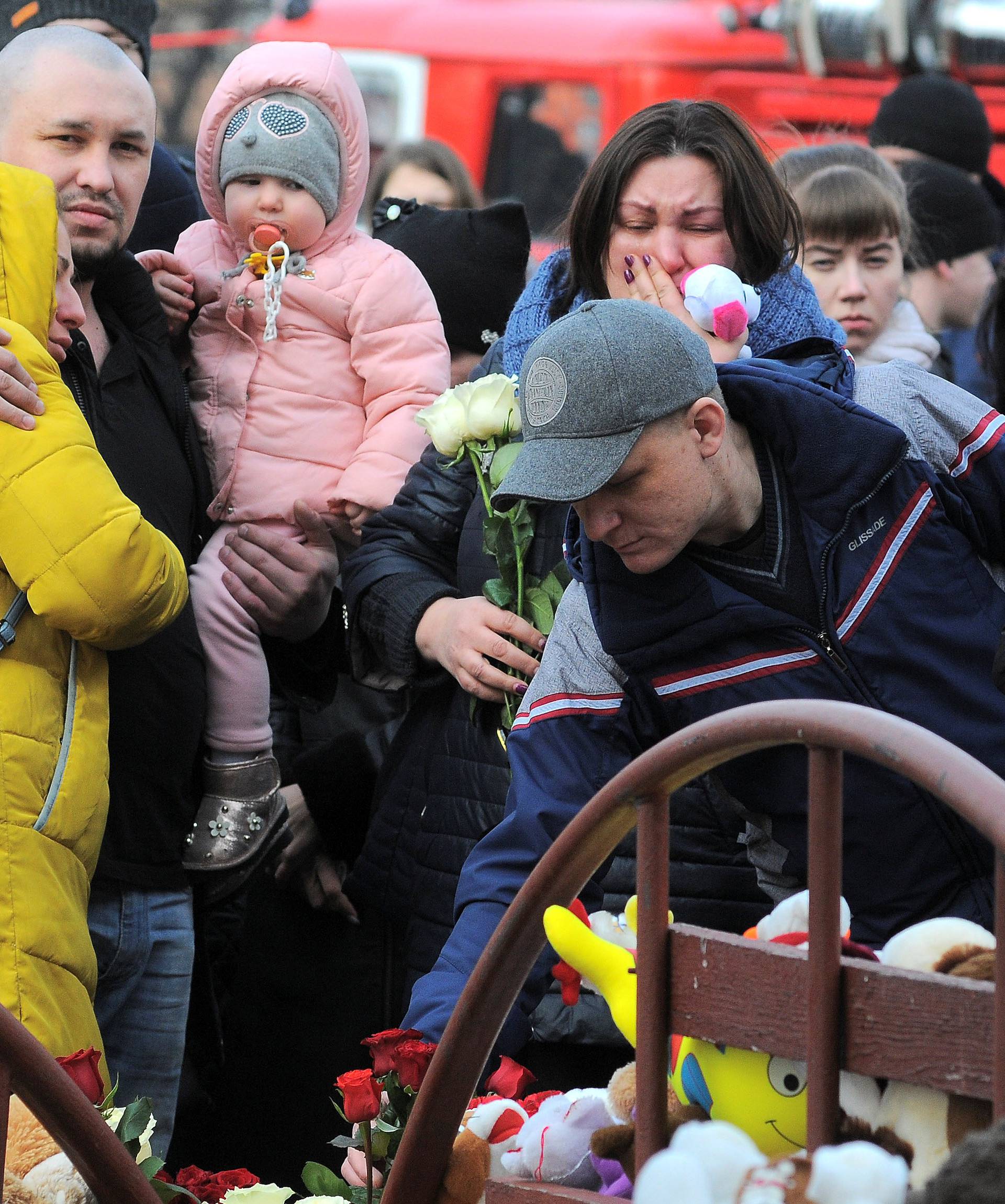 People mourn the victims of a shopping mall fire at a makeshift memorial in the Siberian city of Kemerovo