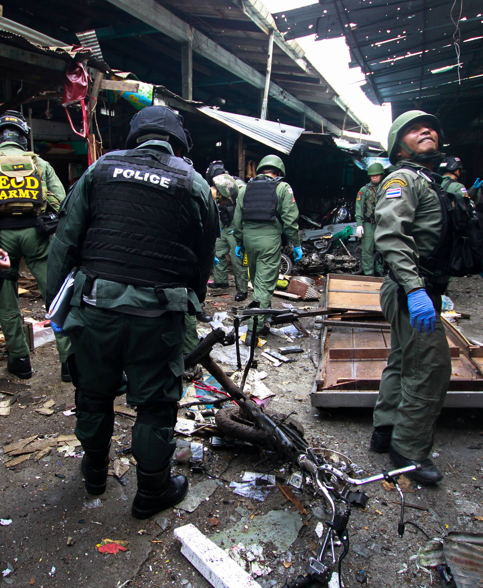 Military personnel and police officers inspect the site of a bomb attack at a market in the southern province of Yala