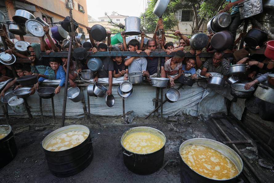 Palestinians wait to receive food from a charity kitchen, amid a hunger crisis, in Gaza City
