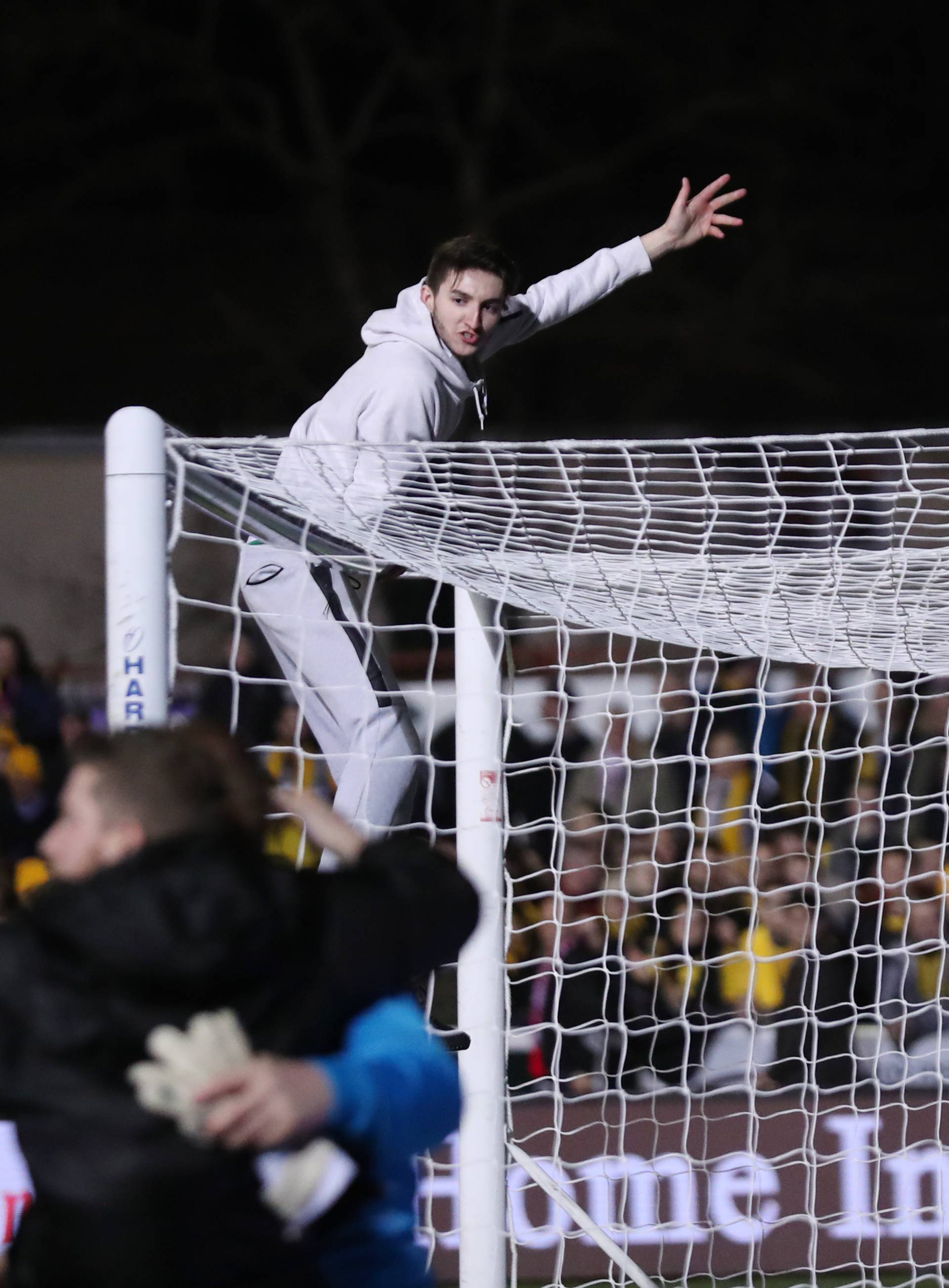 Sutton fans on the pitch and on the crossbar of a goal after the match