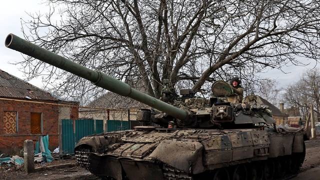 A Ukrainian serviceman gestures as he rides a tank on a road towards the frontline town of Bakhmut in Chasiv Yar